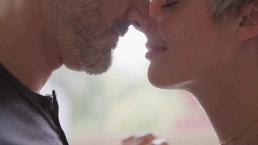 A man and woman face to face touching noses smiling looking like love