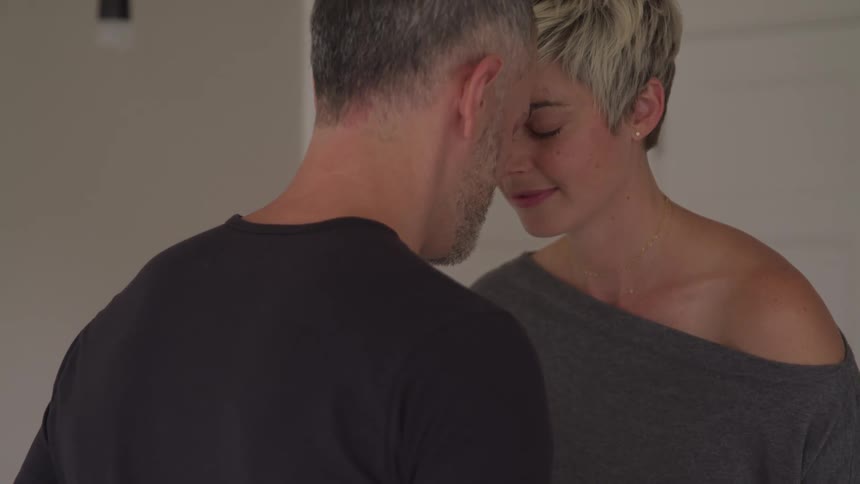 A man and woman sit with their heads touching