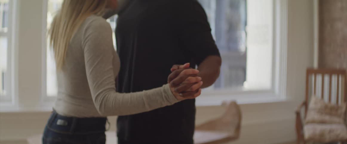 A couple are dancing in the living room