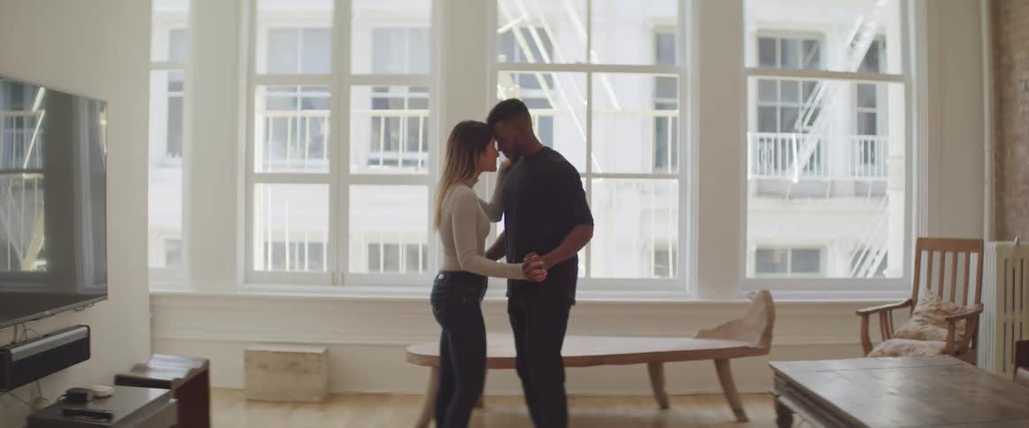 A man and woman slow dance together in their living room