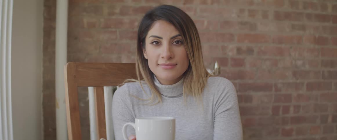A woman is holding a mug by the window