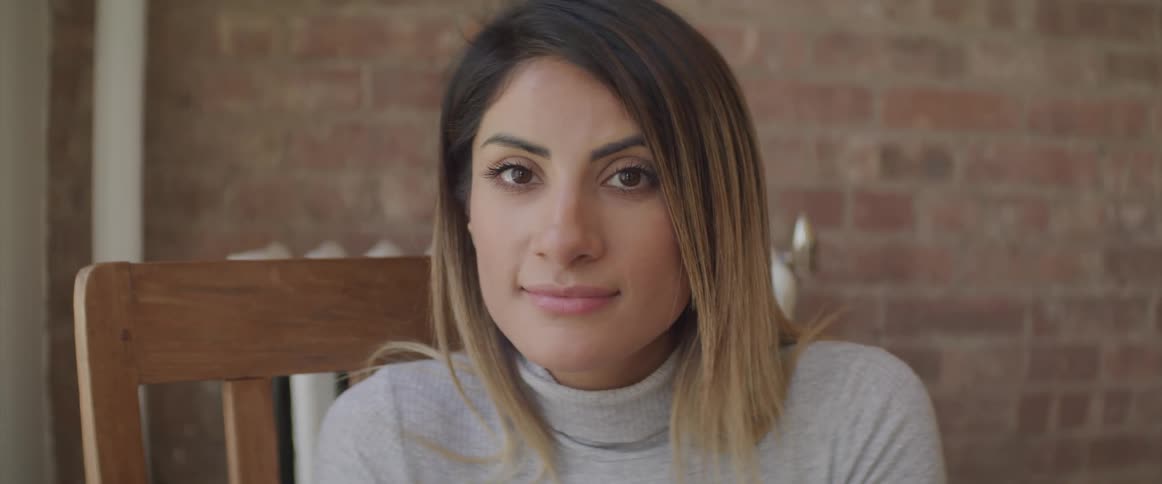 A woman sitting in a chair turns her head forwards and smiles