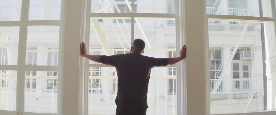 A man stands and looks out a window