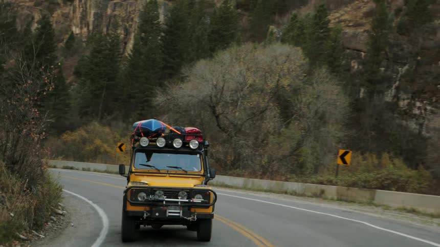 A orange vehicle is riding uphill on a road