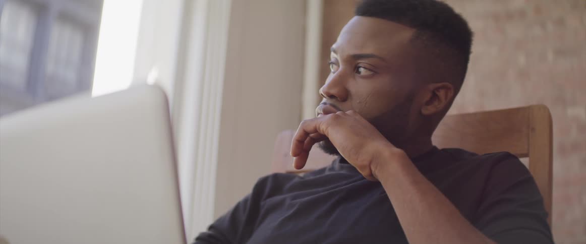 The man sits in front of his laptop