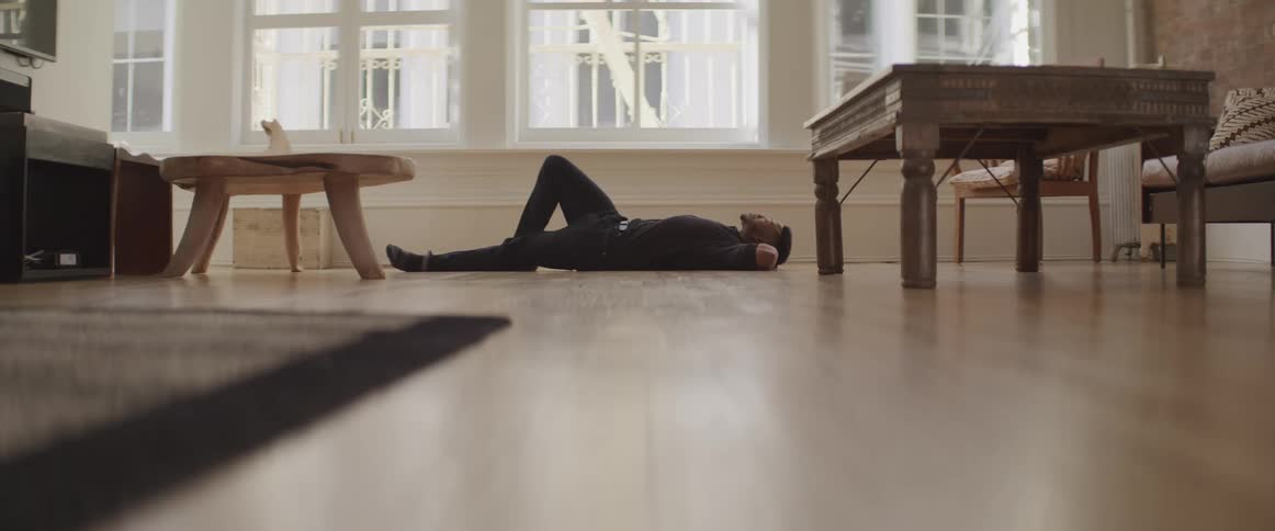 A man lies down on the wood floors of his apartment