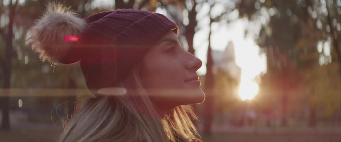 Blonde woman opens her eyes and looks up in the the public park at sunset