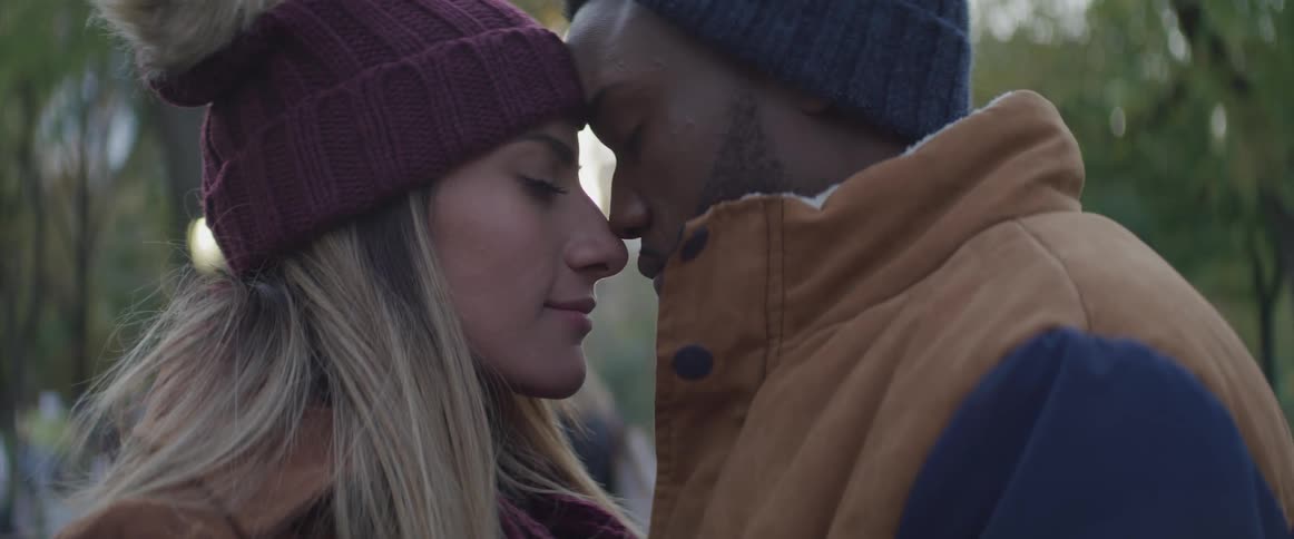 A man and a woman standing face to face with their foreheads touching with their eyes close