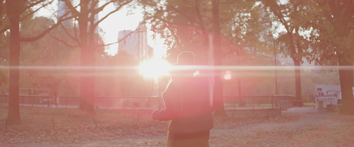 Man and woman wearing jackets dance romantically in the park under the bright sun