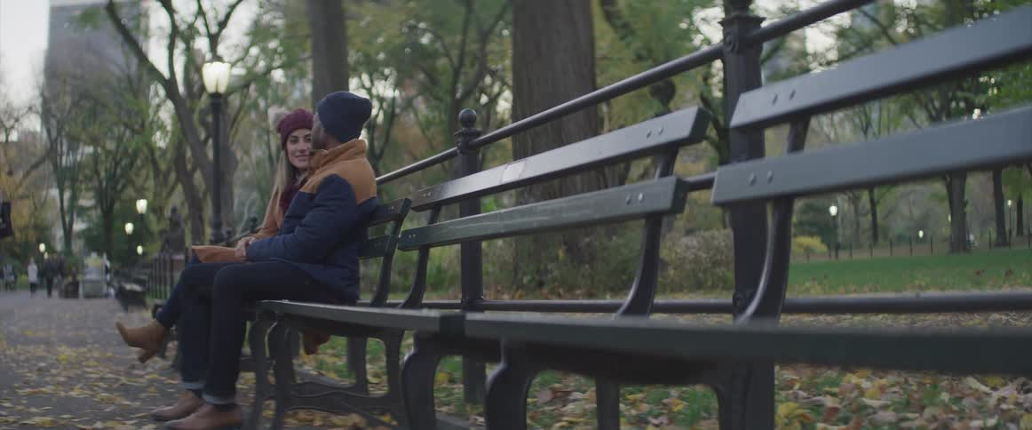 A man and woman sit together on a park bench