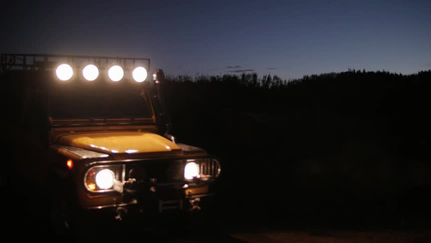 A vehicle drives in the wilderness at night