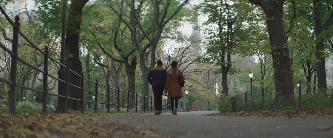 A man and woman walk together through a public park pathway