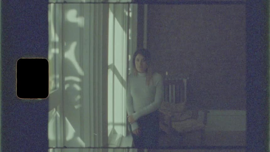 Woman leaning near window and looking out from indoors