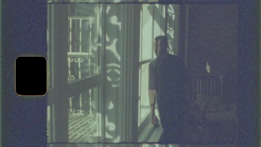 A man gazing out of a window while leaning against the window frame