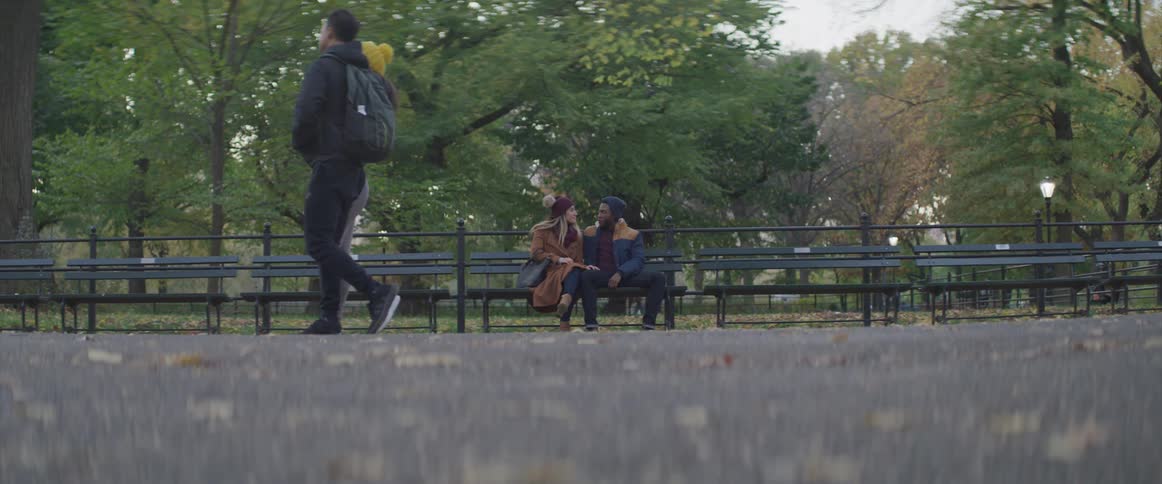 White woman and black man sit on the bench in the public park