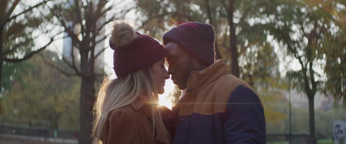 Interracial couple standing touching foreheads at a park in the city