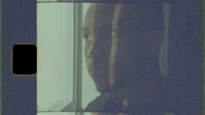Black man looks out the window as he rides on a train