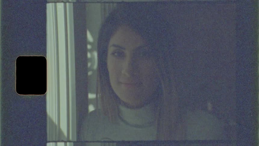 Brunette woman looks out the window and turns her head to the camera