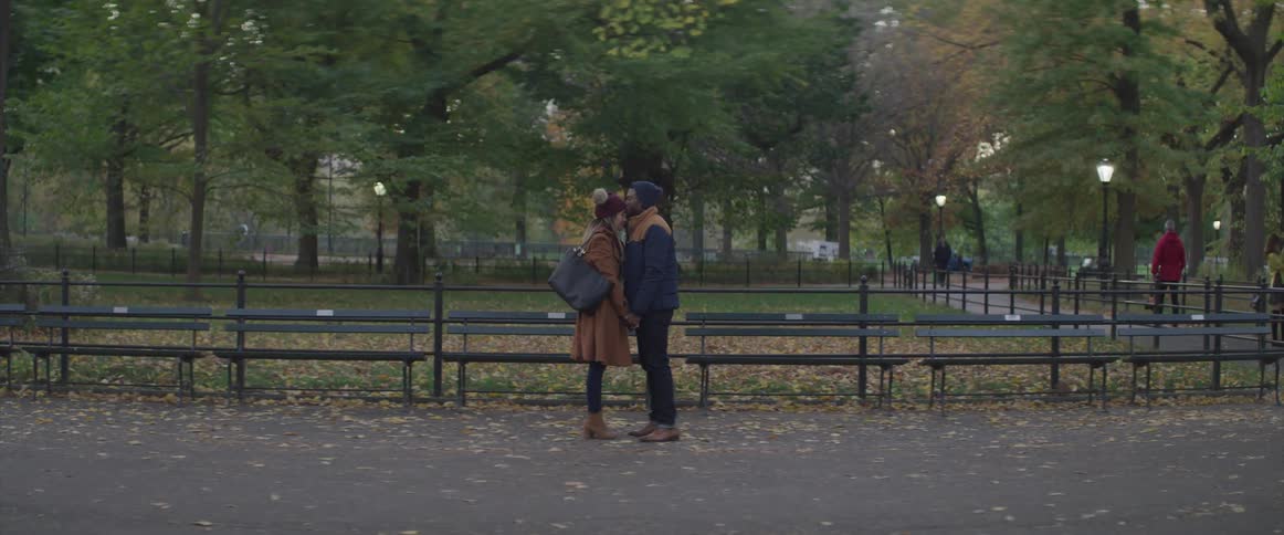 A man and woman hold each other closely standing in a public park