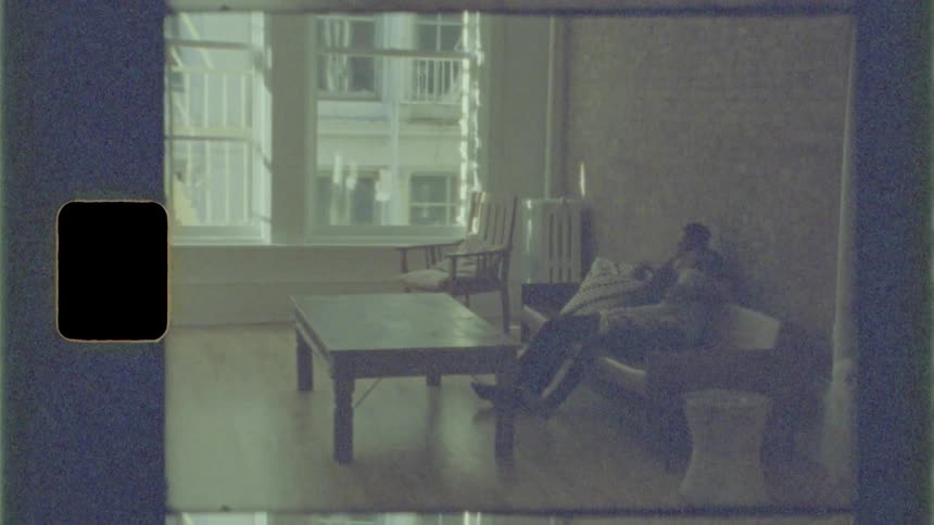 A man sits with his arm around his girlfriends shoulder on the couch in their apartment