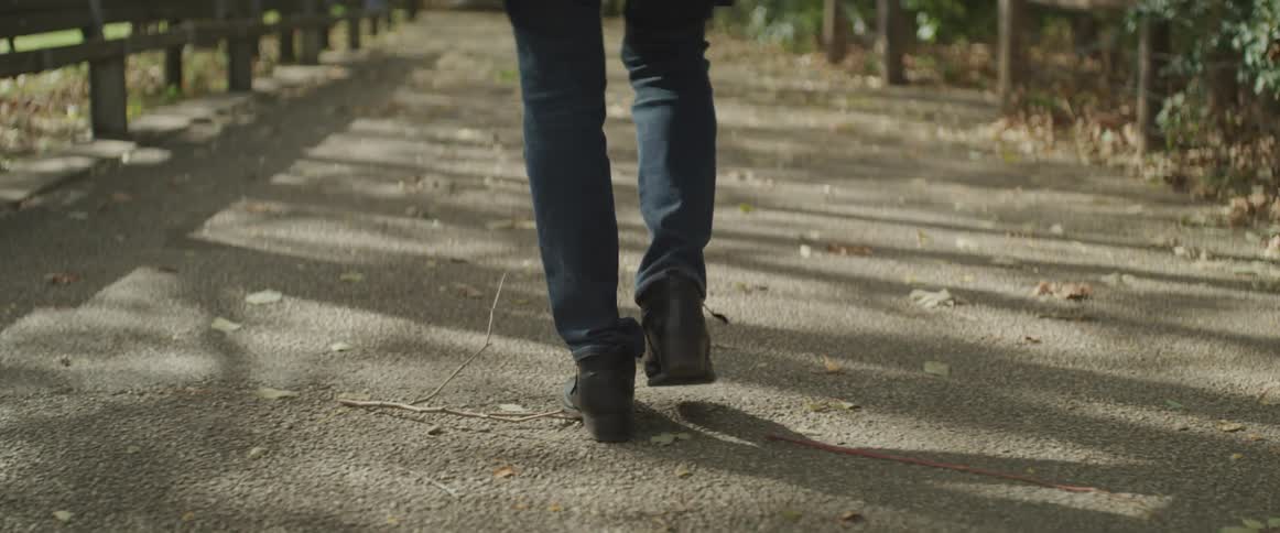 Person wearing jeans and boots walks on path outdoors