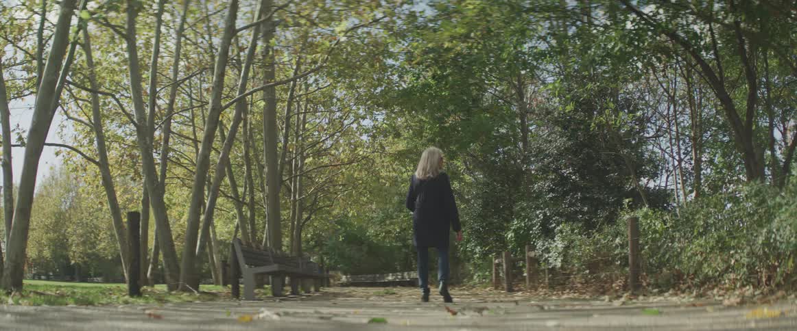 Woman walks through park at day