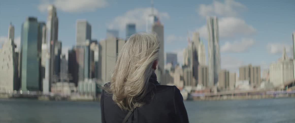 Woman looks at the high rise buildings and skyscrapers across the river