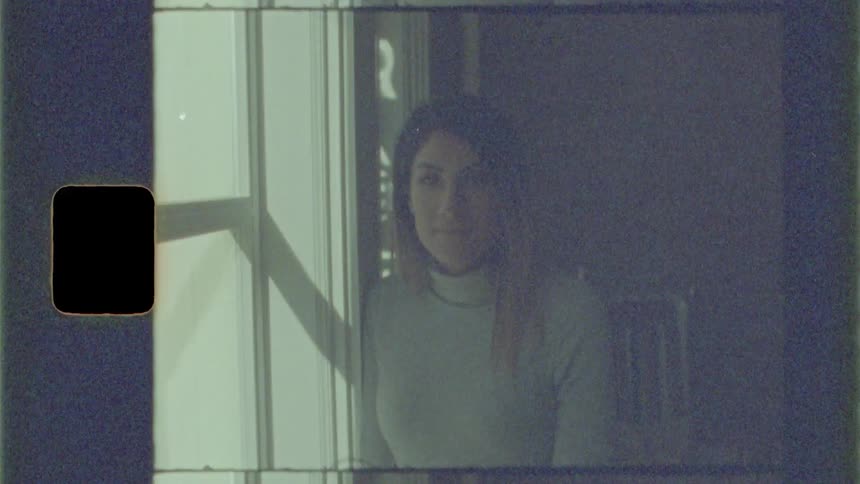 A woman next to a large window in her apartment