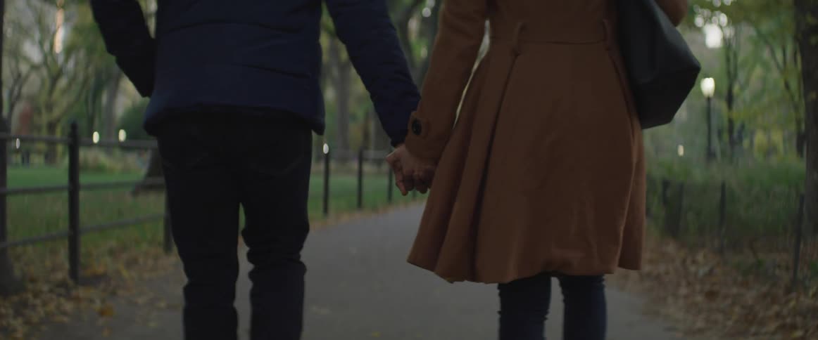 Man and woman holding hands walk in the public park