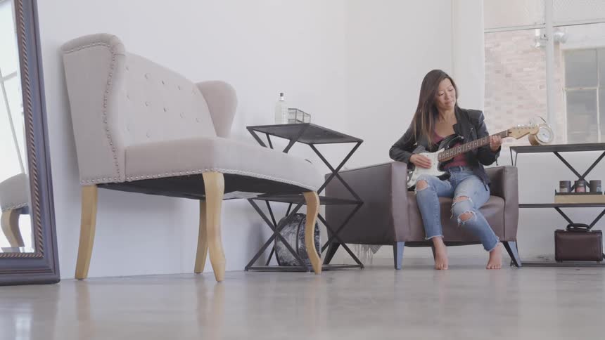 A woman is playing guitar in a house