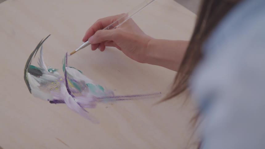 Brunette woman paints on pale wooden board