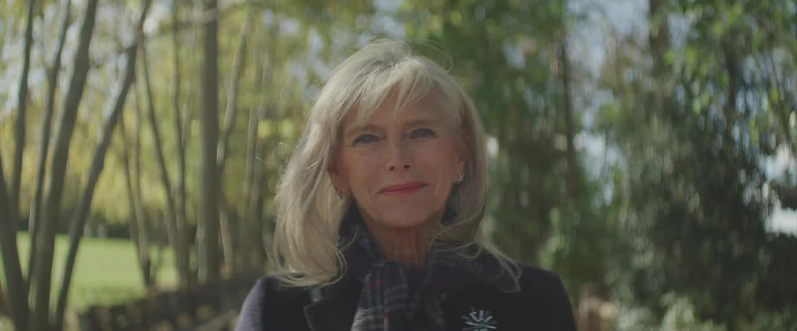 The woman smiles near the trees