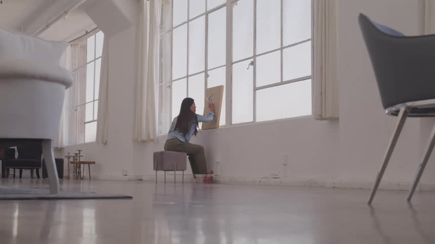 A woman paints in her living room