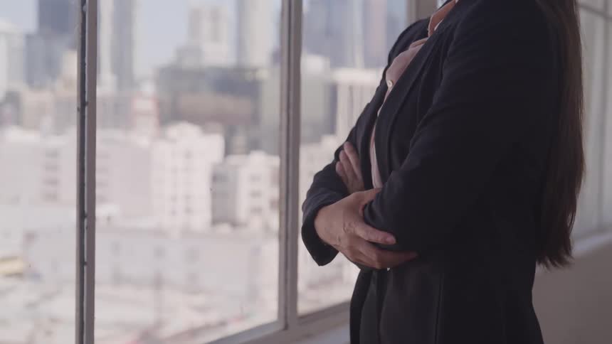 A woman is looking out a window in an office