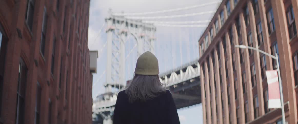 Blonde woman standing in the street looks at the manhattan bridge