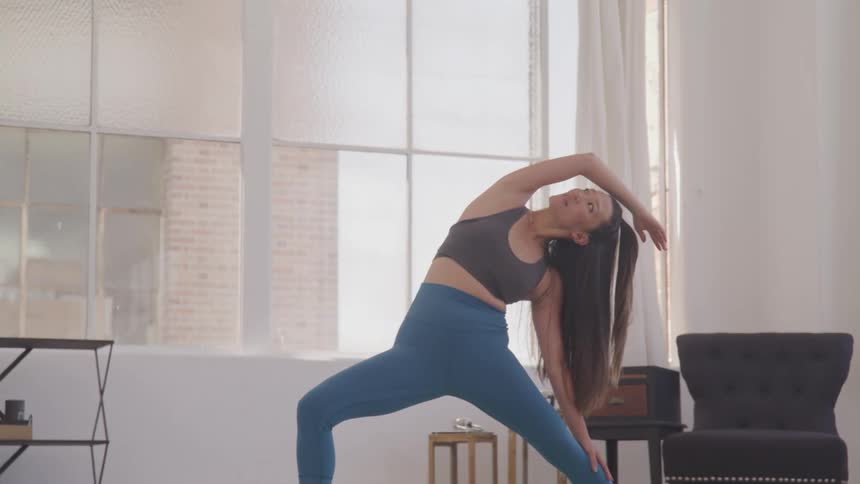 A woman in a room with a large window stretching