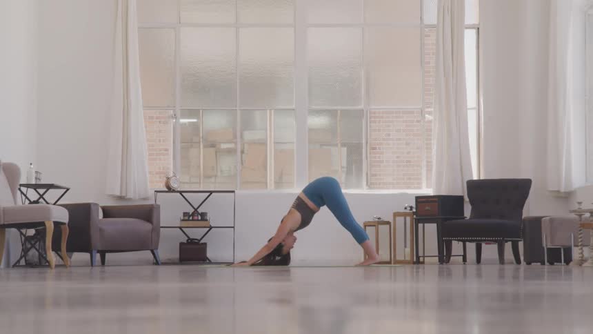 Woman doing yoga in front of large window indoors