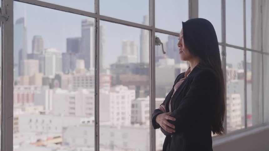 Asian businesswoman looks out the window in the office