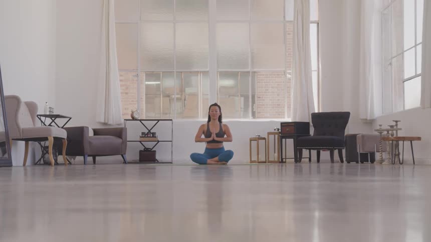 Asian woman sitting on the ground does yoga in the living room at home