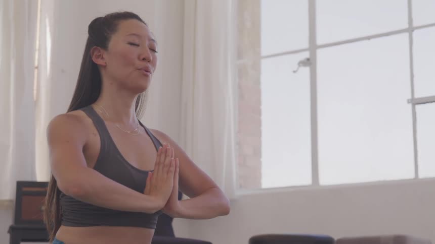 A woman sits and lifts her arms and claps them in meditation
