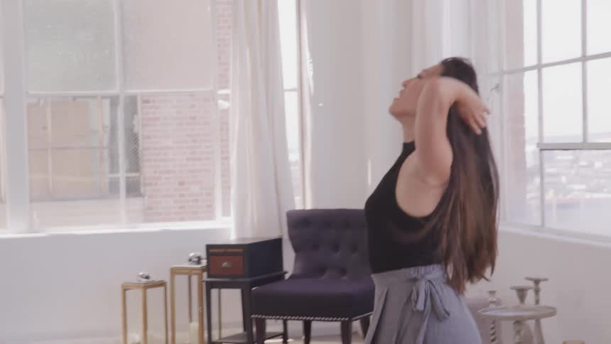 A woman dances around in her living room or studio