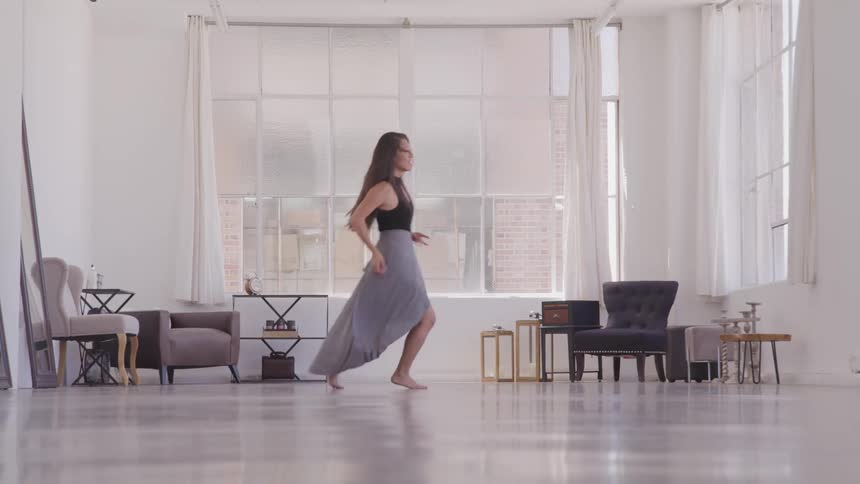 Asian woman performs a graceful dance in the living room at home