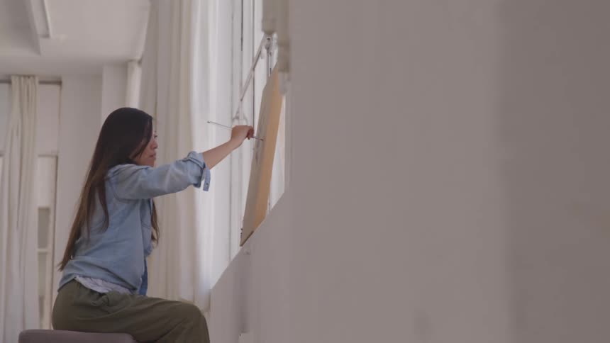 Asian female painter paints a canvas in the workshop