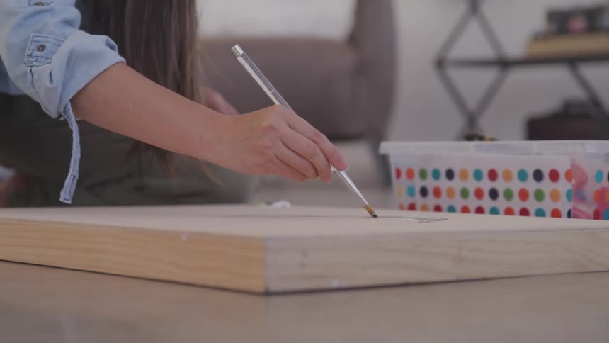 A woman is painting with a brush