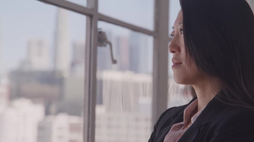 Asian businesswoman looks out the window in the office