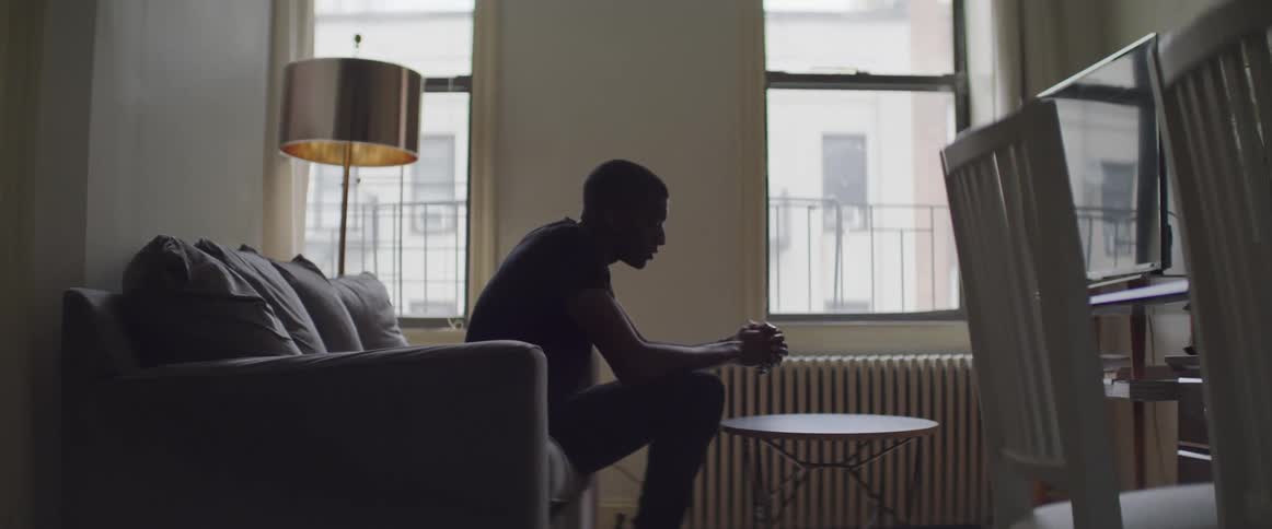 Black man sitting on the sofa watches television at home