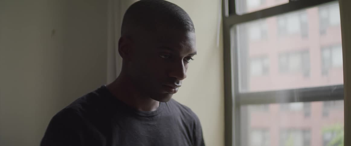 Black man looking down at his feet raises his head in the room