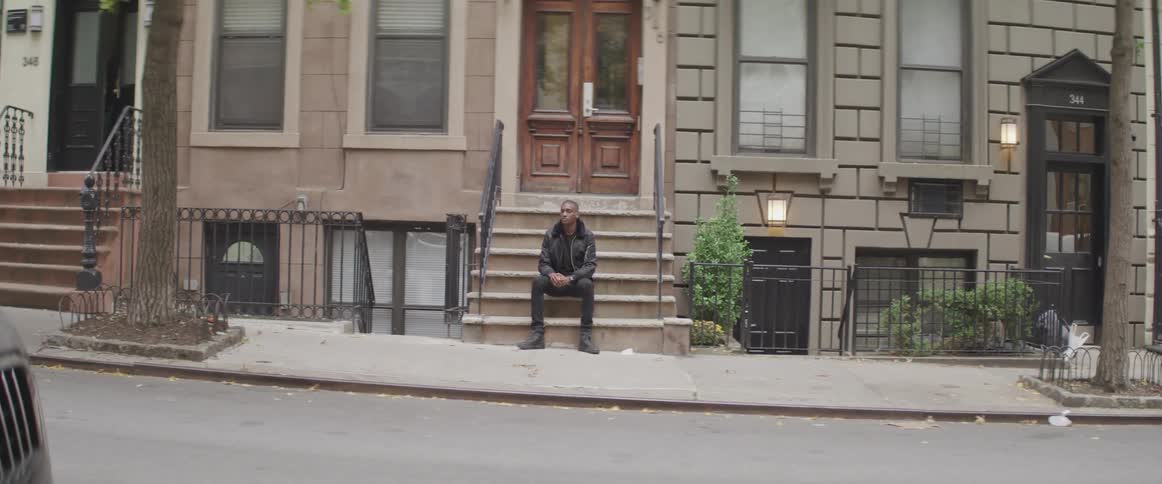 A man sits on outdoor steps in front of a city home
