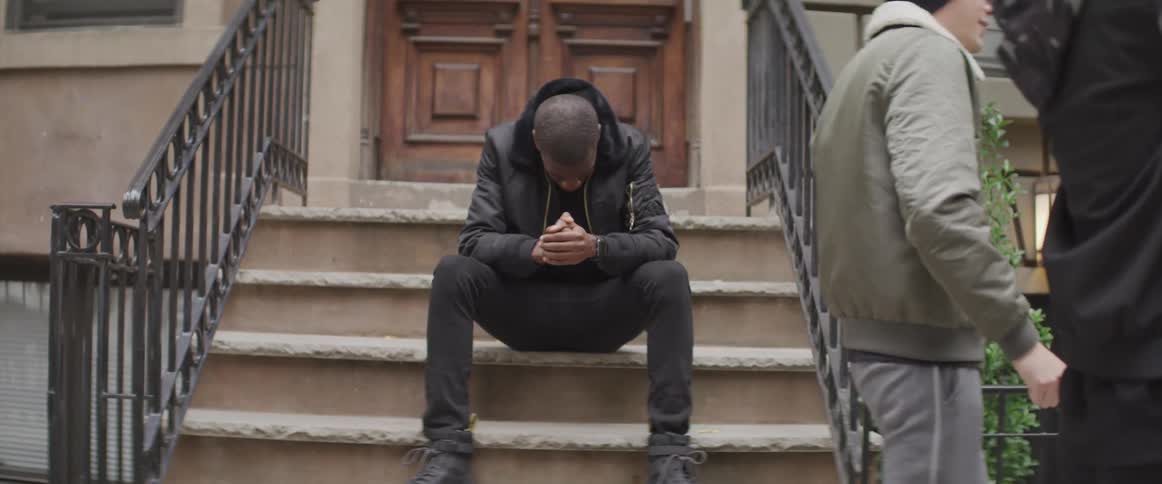 Young man sitting on the stairs in front fo a building