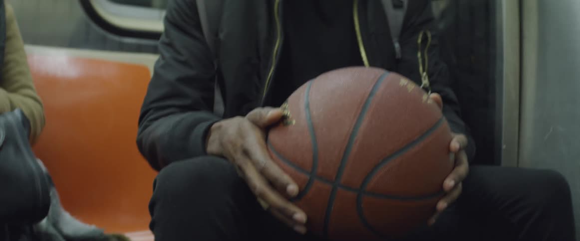 A person holding a basketball while riding in a subway train